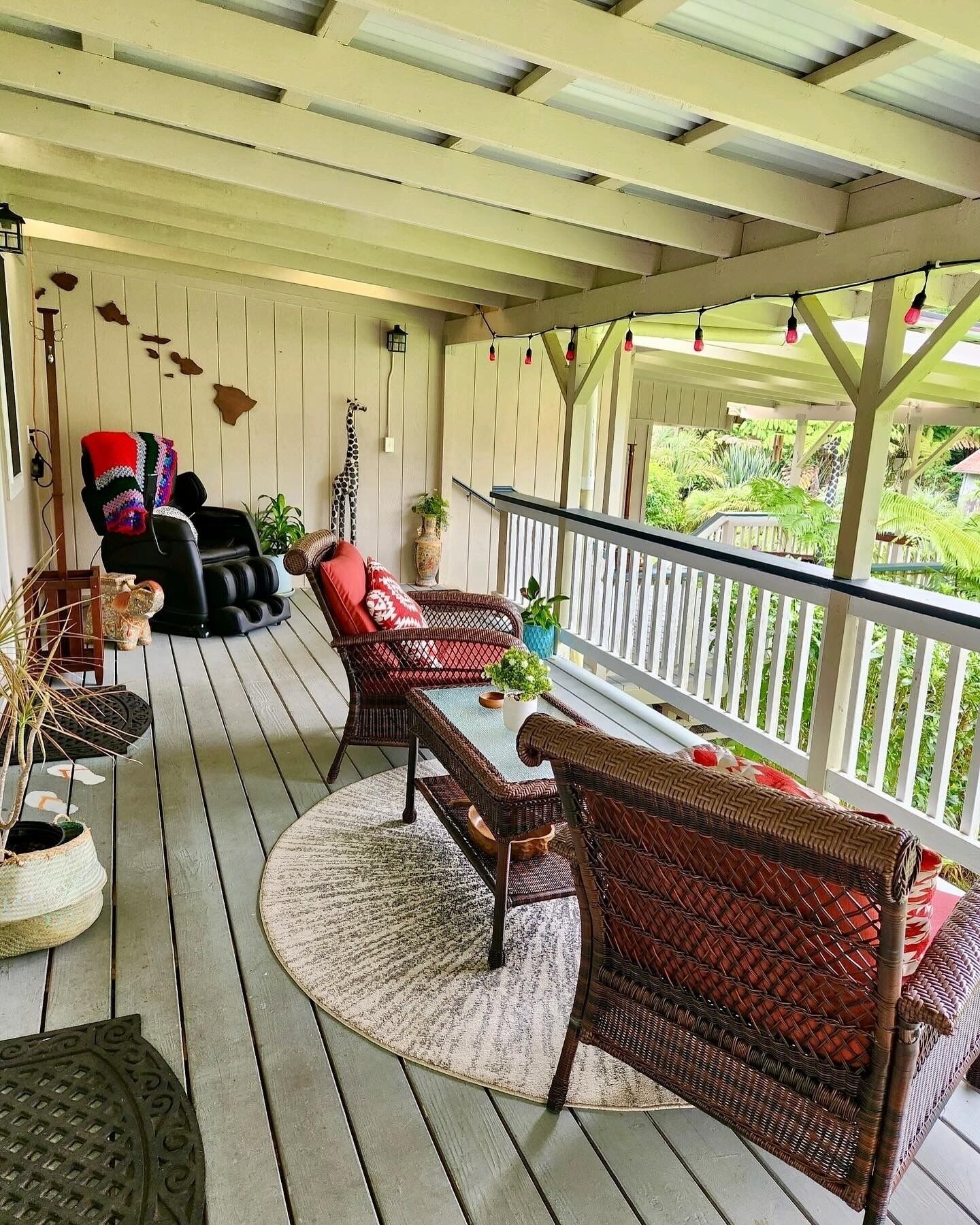 A covered porch with wicker furniture, a table, and potted plants.