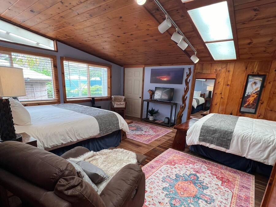 A cozy room with two beds, a sofa, and a large rug.