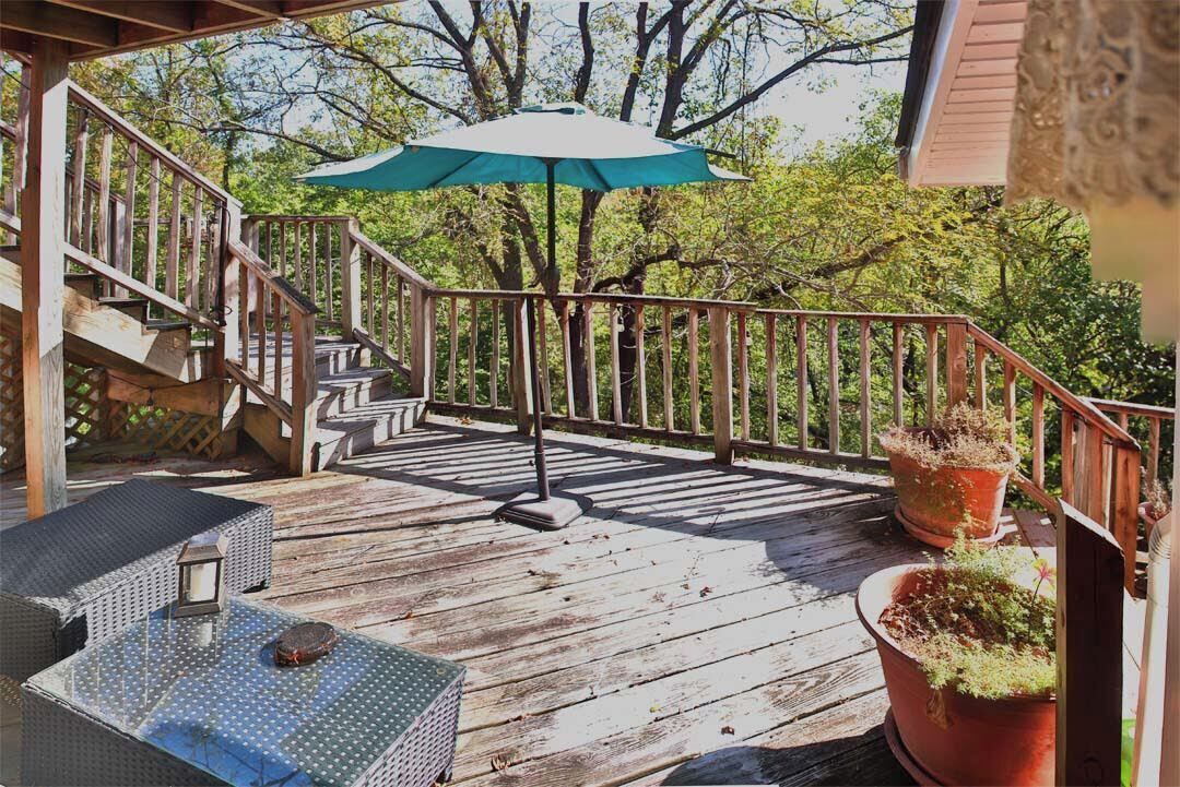 A wooden deck with a staircase, outdoor furniture, and potted plants.