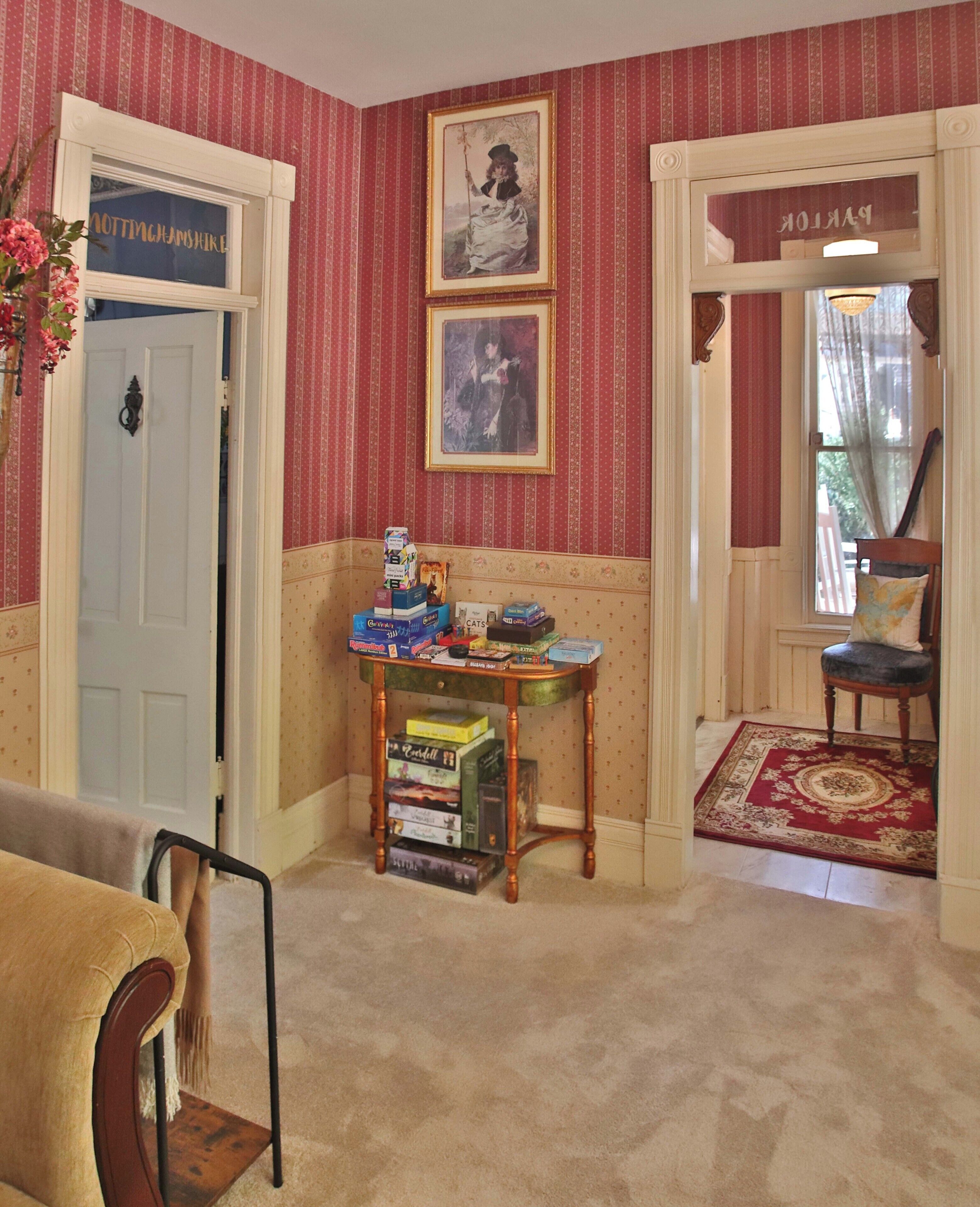 A room with striped wallpaper, a table with board games, a chair, and a door labeled "Nottinghamshire".