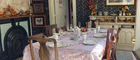 A dining room with a table set for six, surrounded by wooden chairs.