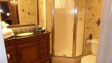 A bathroom with a wooden vanity, a glass shower enclosure, and a toilet.