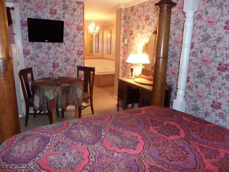 Un dormitorio con una cama grande, un escritorio con lámpara, una silla y un televisor en la pared.