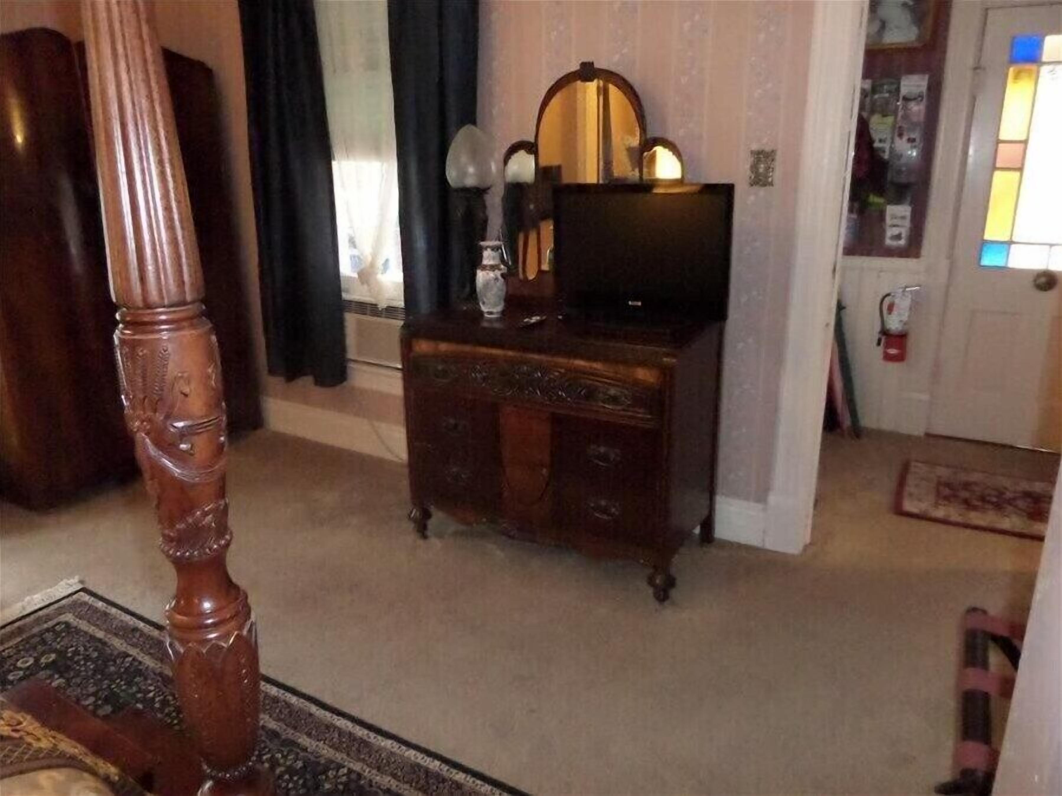 Una habitación con un aparador de madera, un televisor, un espejo y una puerta con ventana.