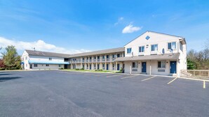 A motel with multiple rooms, a large parking lot, and a clear blue sky. - Econo Lodge Bethel - Danbury (Bethel)