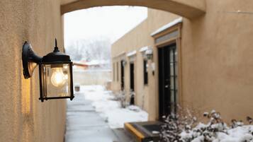 A corridor with a wall-mounted light fixture, a door, and snow on the ground.
