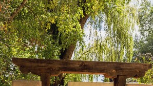 A wooden pergola entrance to a patio area with a pathway leading to outdoor seating.