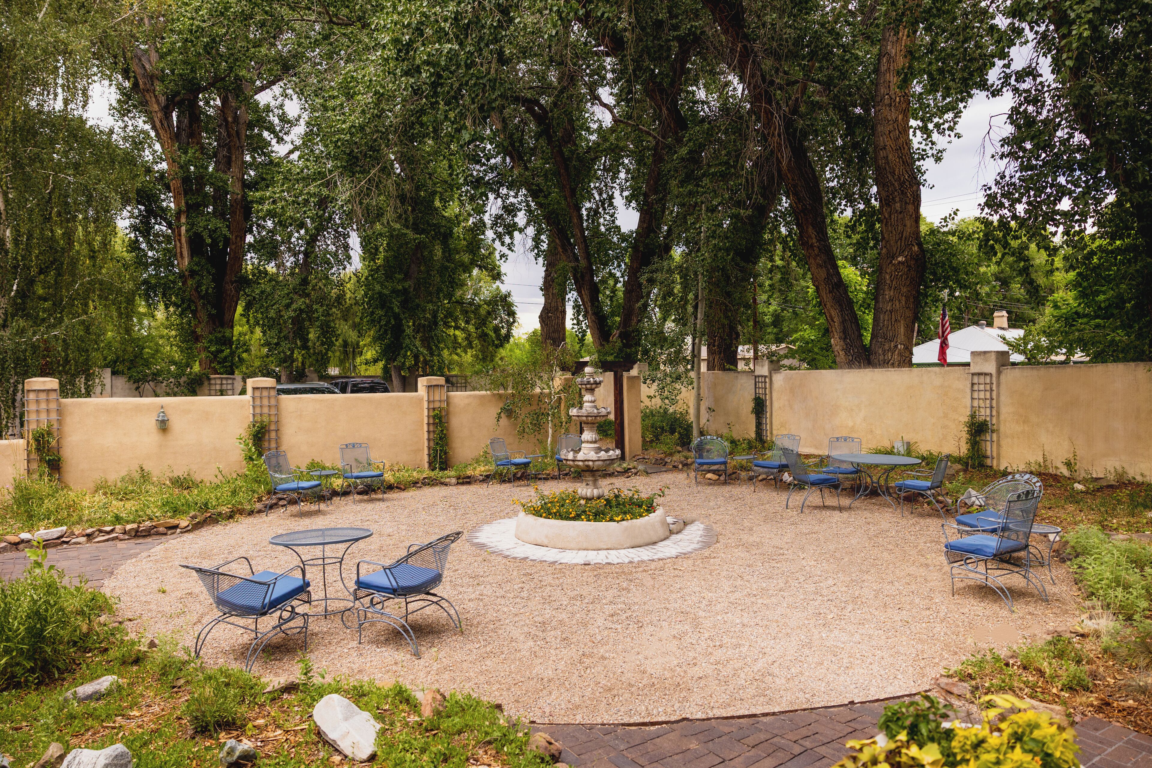 An outdoor patio with a circular seating area, a central fountain, and surrounding greenery.