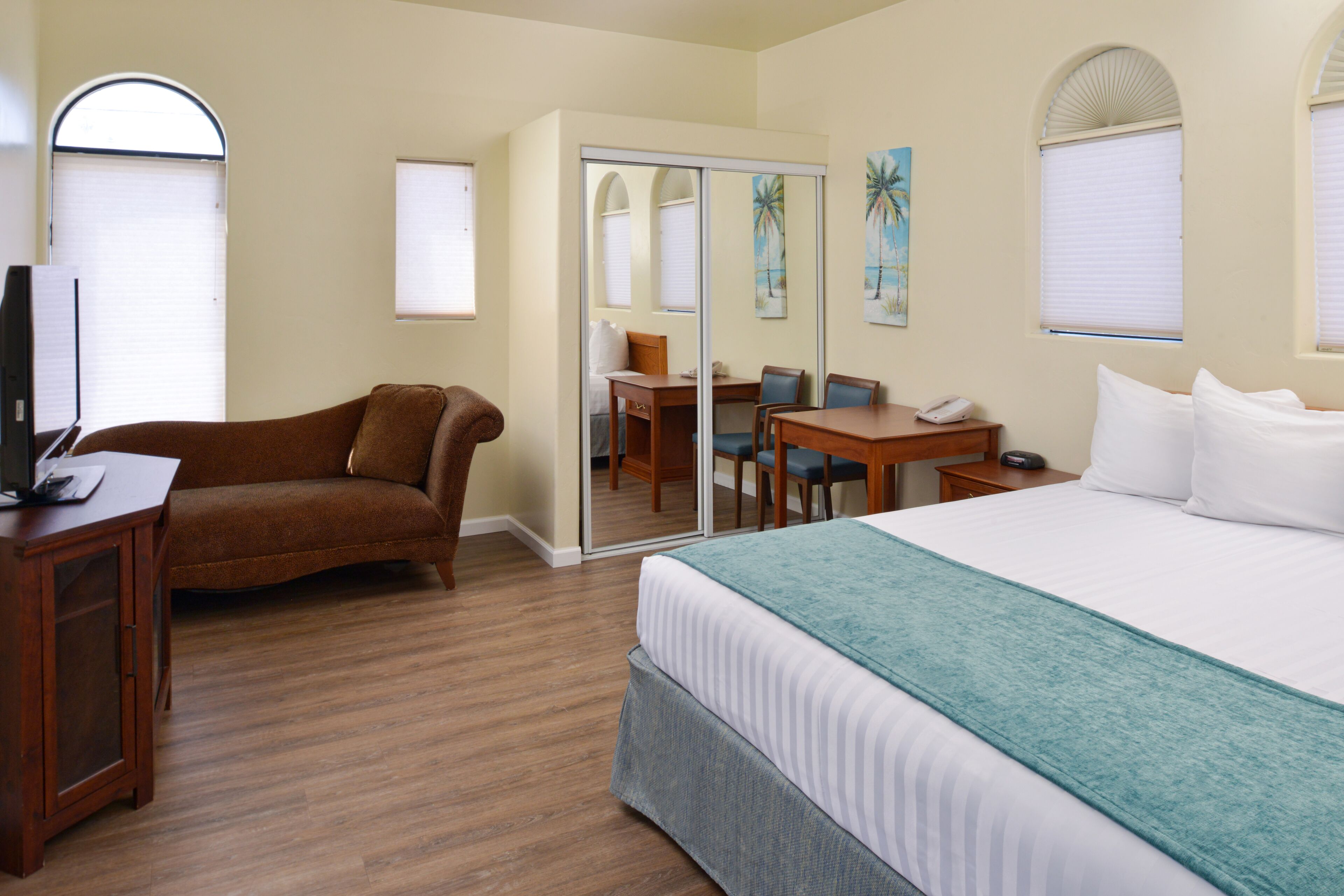Una habitación de hotel con una cama, un escritorio, una silla, un sofá y una televisión.