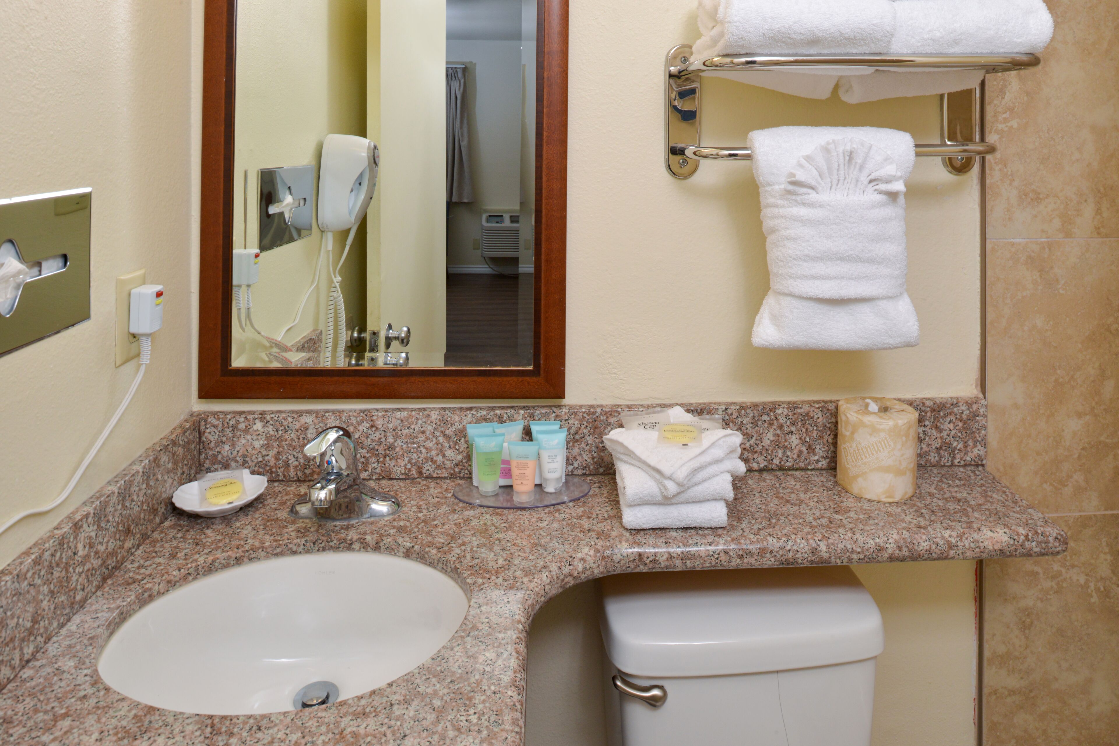 A bathroom with a sink, mirror, towel rack, and toiletries.