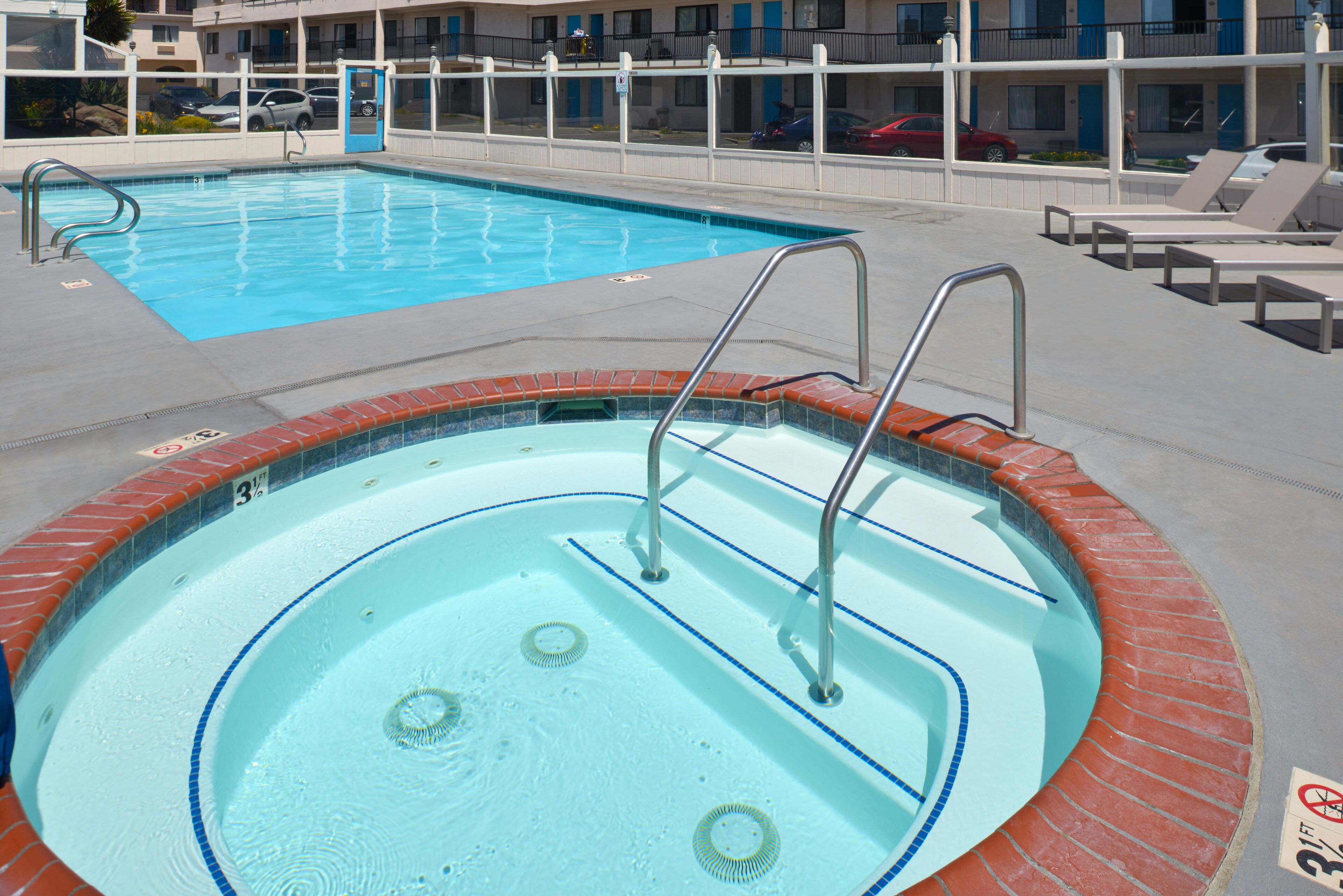 Una piscina con borde de ladrillo y escaleras metálicas.