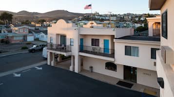 A multi-story building with a flag, a parking lot, and a street view.