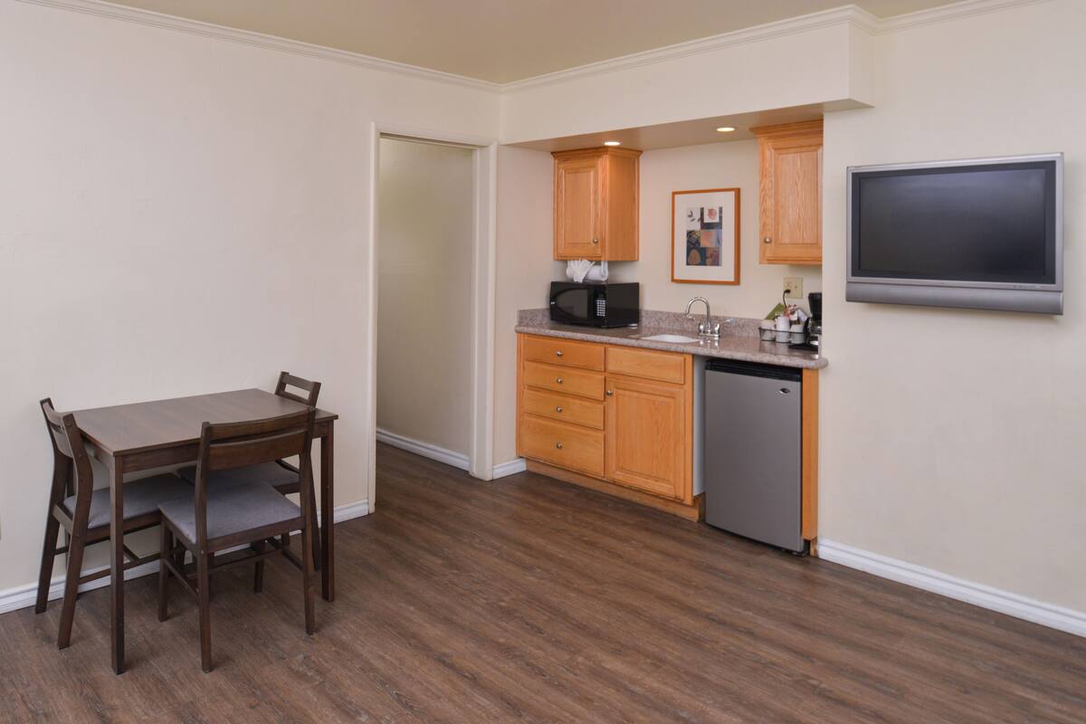A compact kitchen with wooden cabinets, a built-in microwave, and a dishwasher.