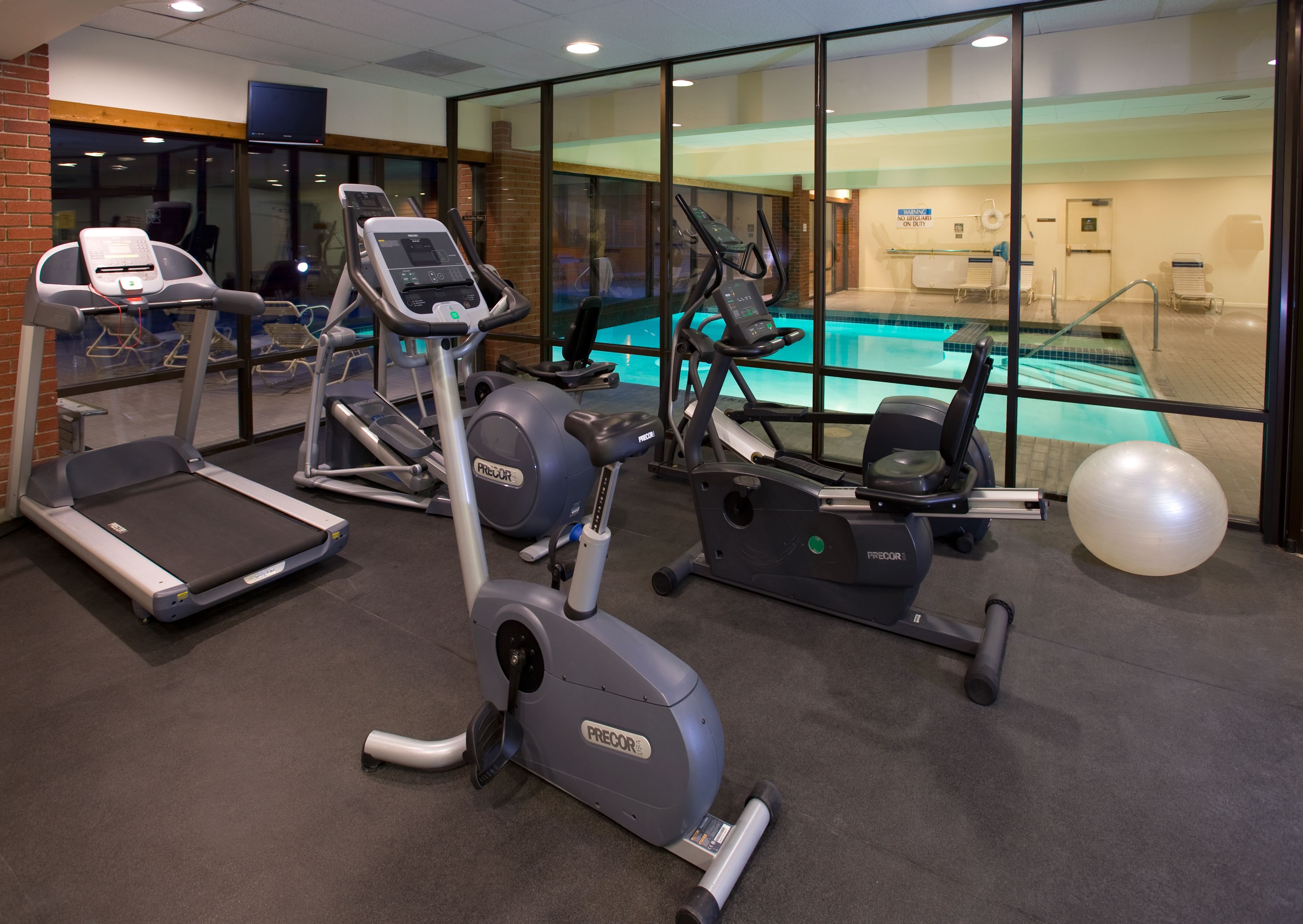 A gym with treadmills, elliptical machines, and a pool.