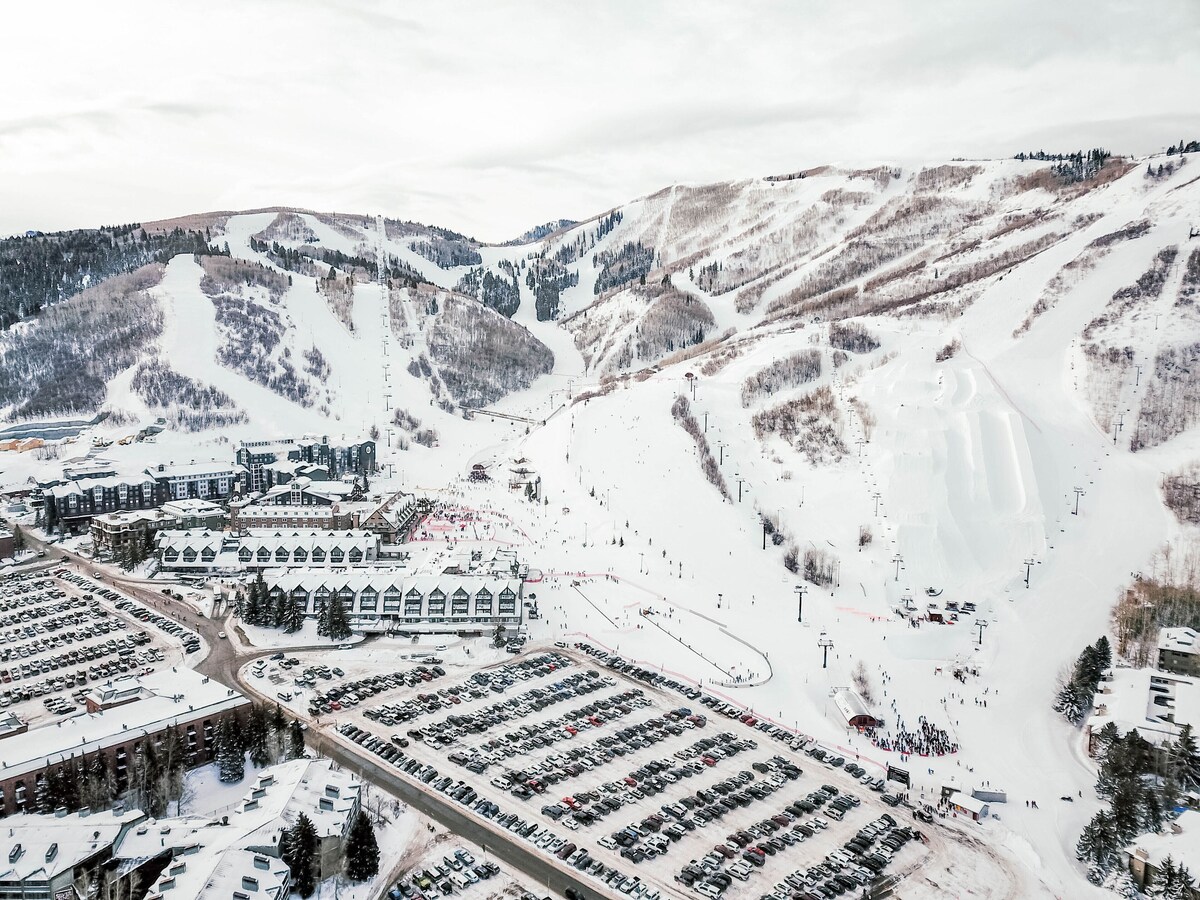 Aerial View of Park City Resort's Mountain Base area with slopes, parking, lifts, halfpipe, and terrain parks visible.