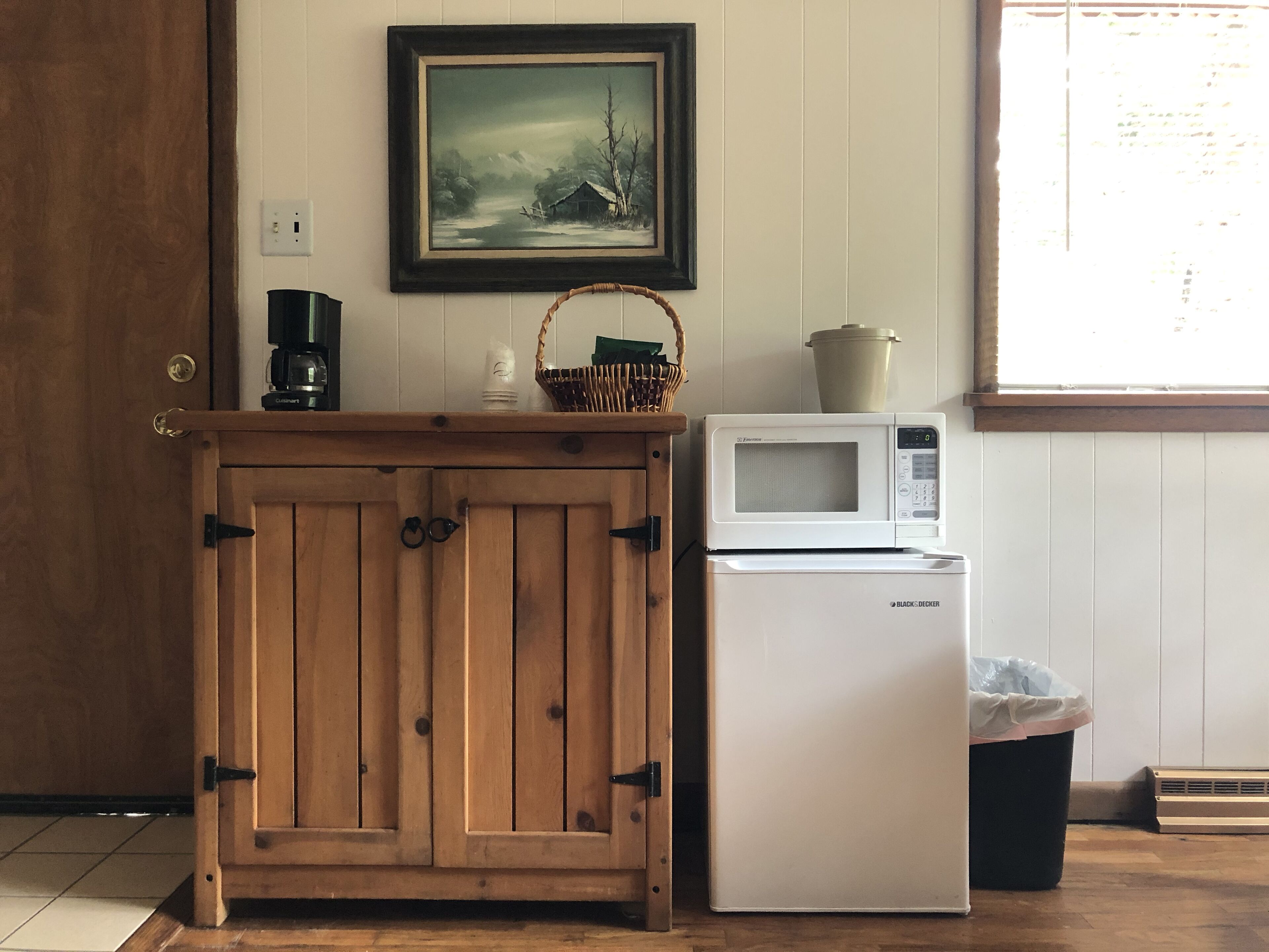 A kitchen with a wooden cabinet, a microwave, and a refrigerator.