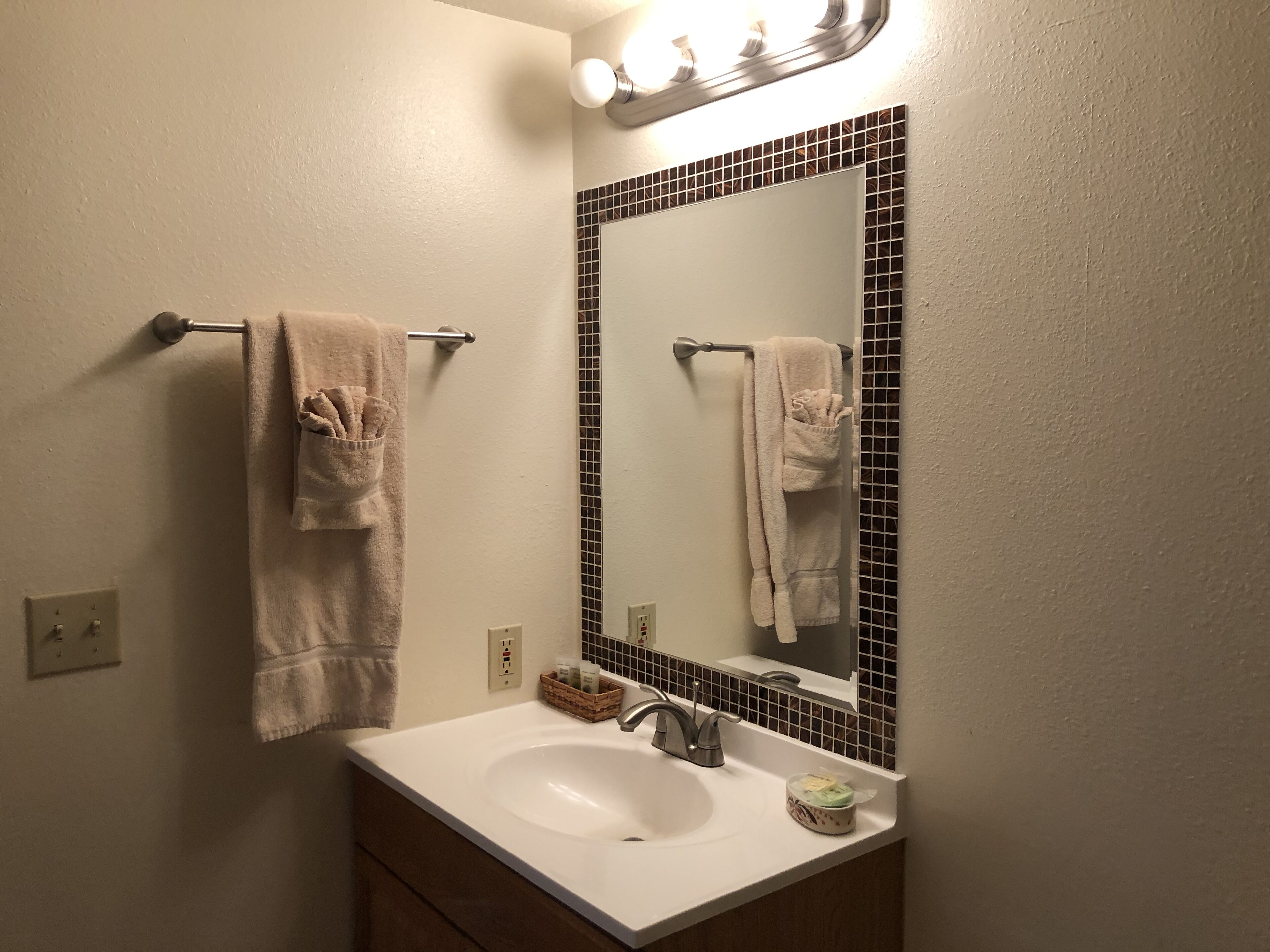 A bathroom with a white sink, a mirror with a black frame, and two towels hanging on a towel rack.