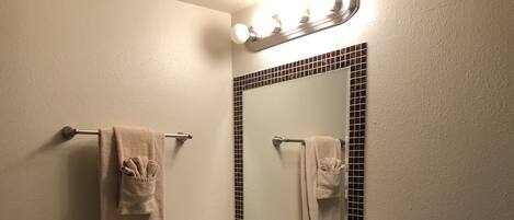 A bathroom with a white sink, a mirror with a black frame, and two towels hanging on a towel rack.