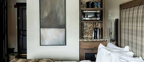 Une chambre d’hôtel avec un grand lit, une œuvre d’art accrochée au mur, un four à micro-ondes intégré et un petit coin salon.