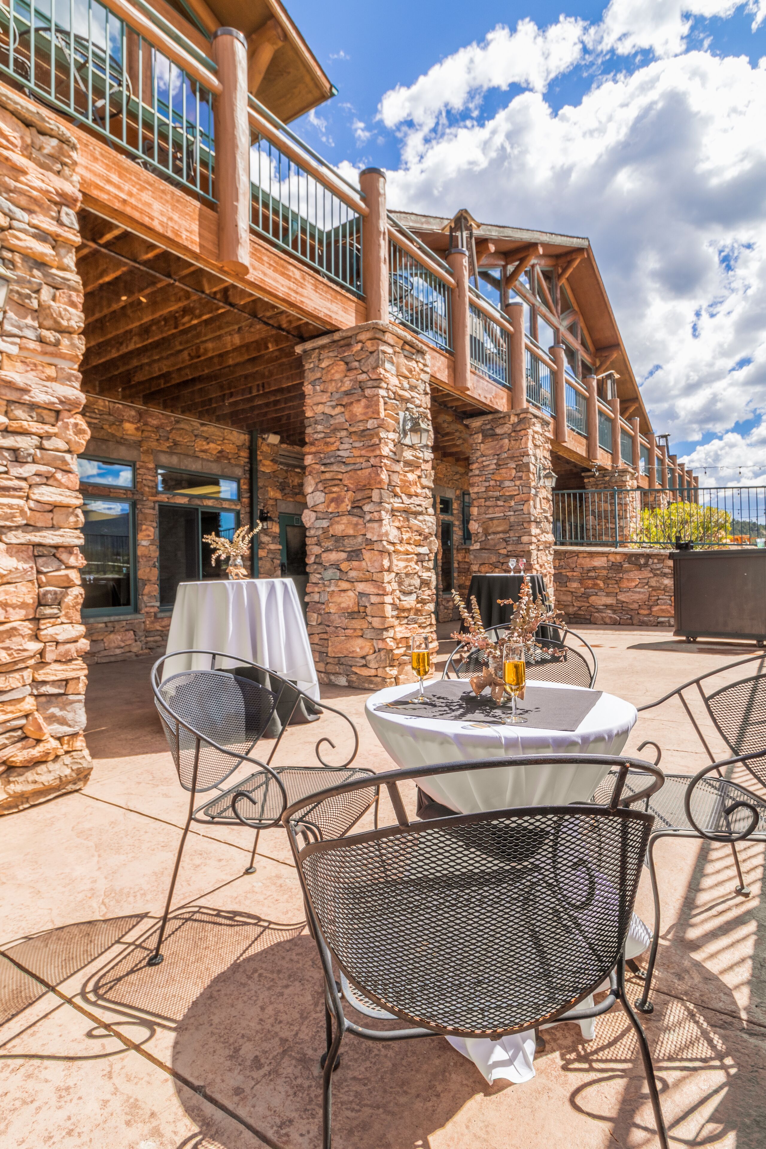 An outdoor patio with stone pillars, metal chairs, and a table set for dining.
