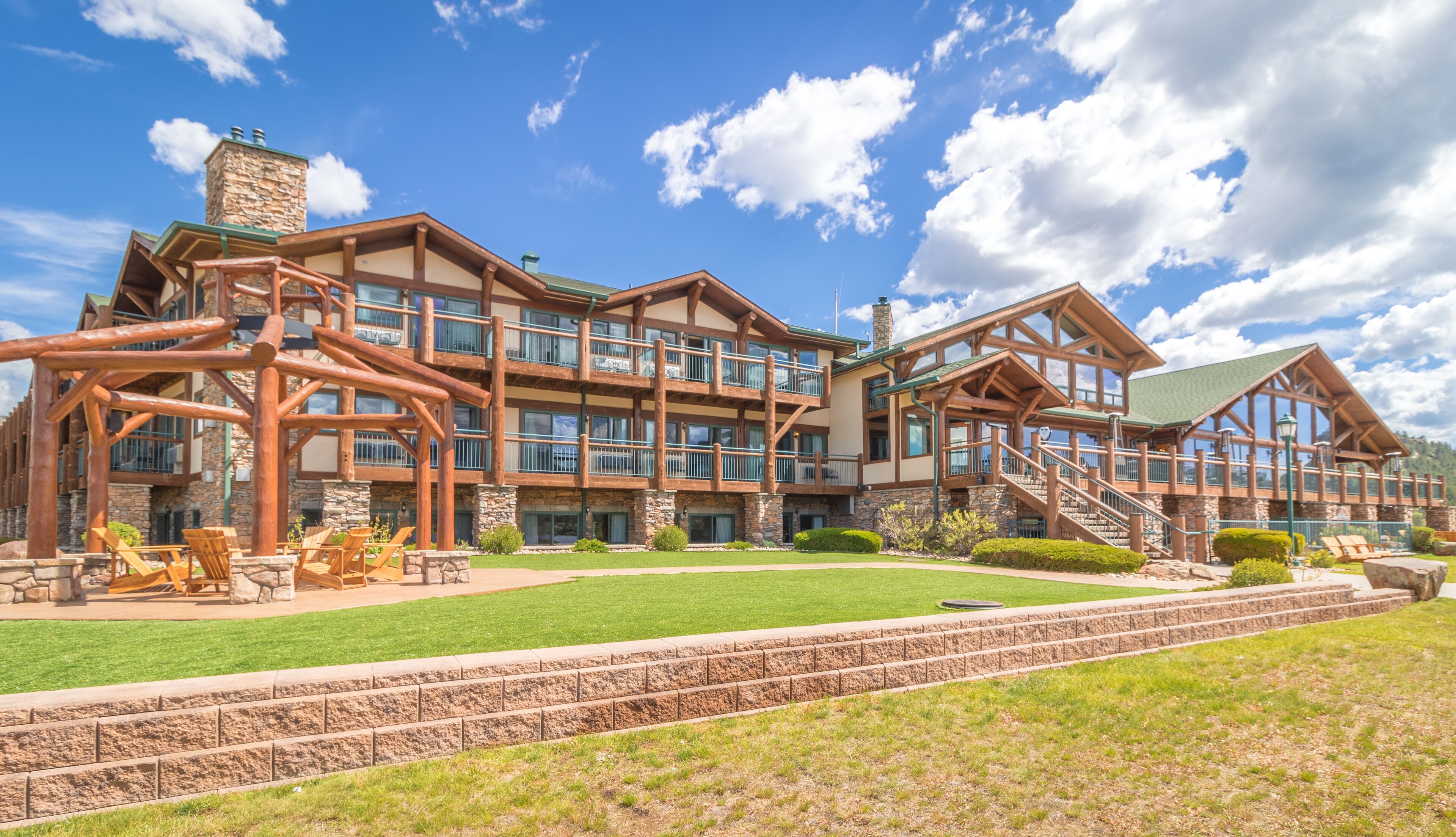 Un grand chalet doté de nombreux balcons, d’une façade en pierre et d’une pelouse bien entretenue.