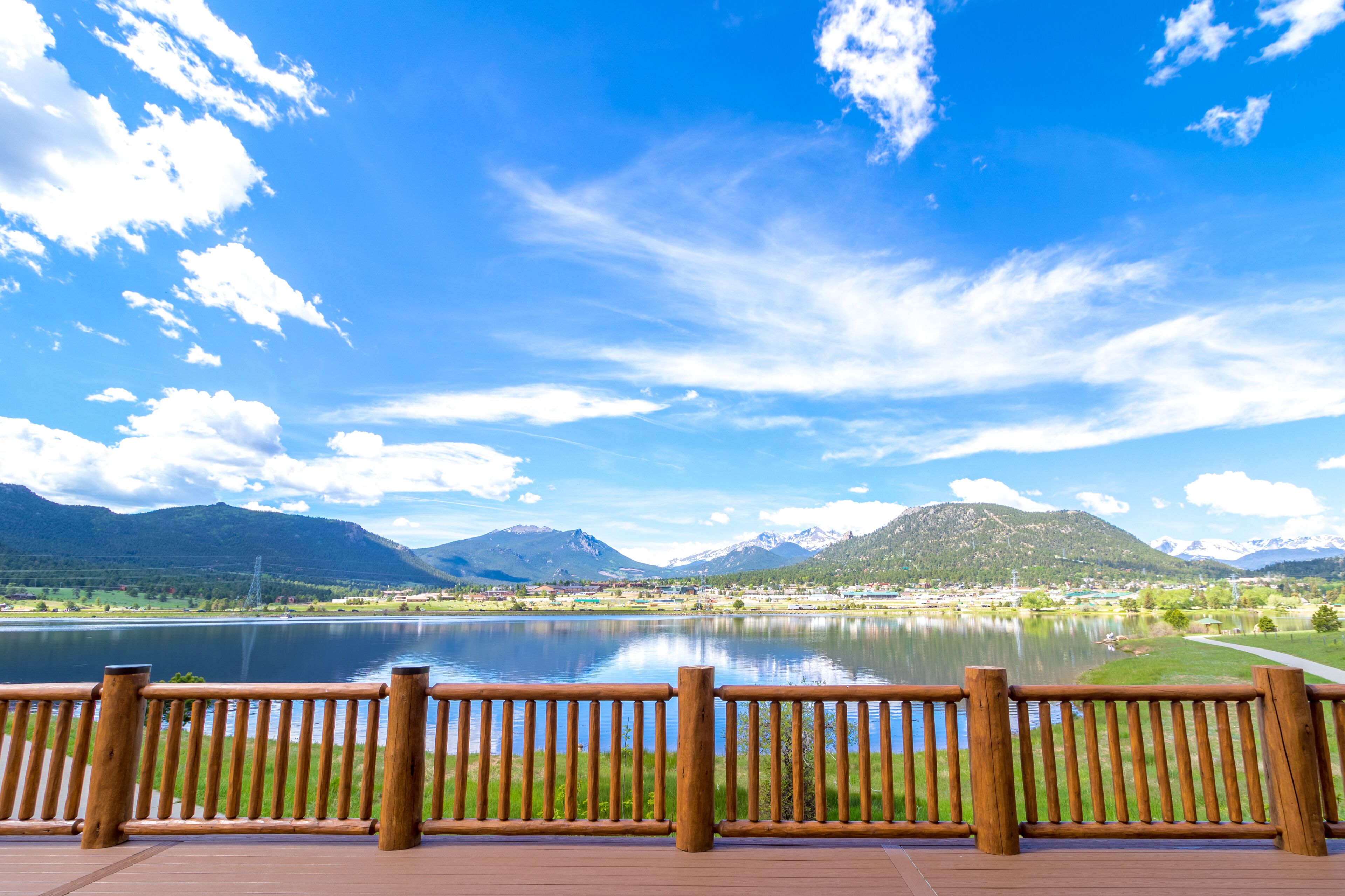 A lakeside view with a wooden deck and a mountain backdrop.