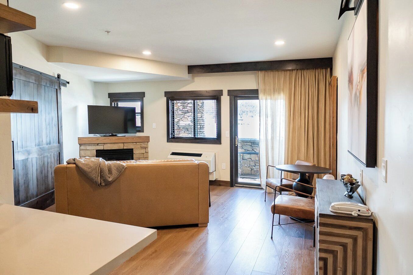 Een moderne woonkamer met een bank, een televisie, een open haard en een eethoek met een tafel en stoelen.