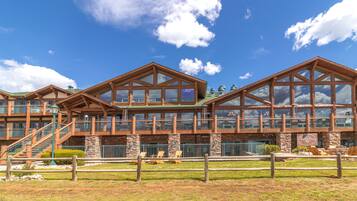 Un grand bâtiment de plusieurs étages, de style chalet, avec une façade en bois remarquable, de nombreux balcons et une base en pierre.