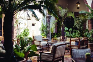 A cozy patio area with wicker furniture, potted plants, and a stone wall. - Casa de Sierra Nevada, A Belmond Hotel, San Miguel de Allende (San Miguel de Allende)