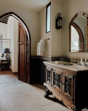 A bathroom with a wooden vanity, a large mirror, and a towel rack.