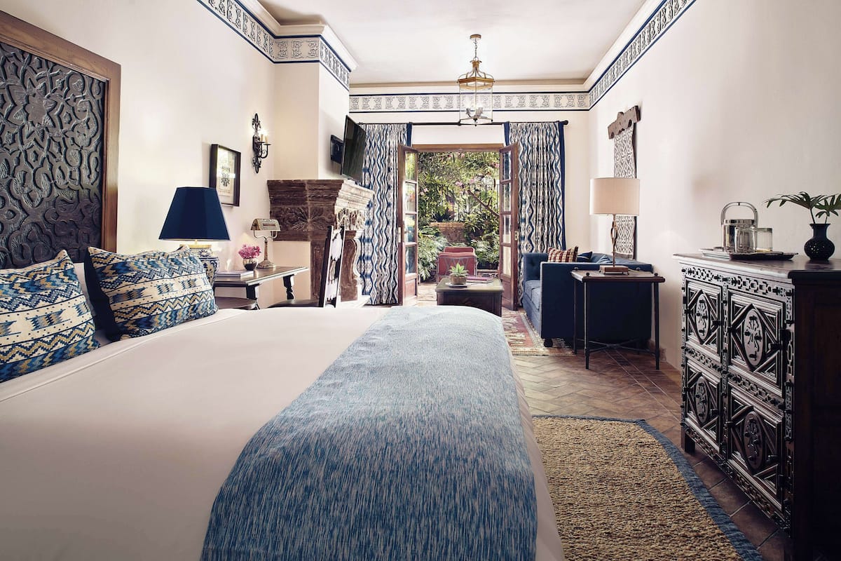 Un dormitorio con una cama grande, un escritorio y vista a un jardín.
