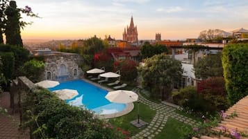 Alberca al aire libre, sombrillas en la alberca y camastros