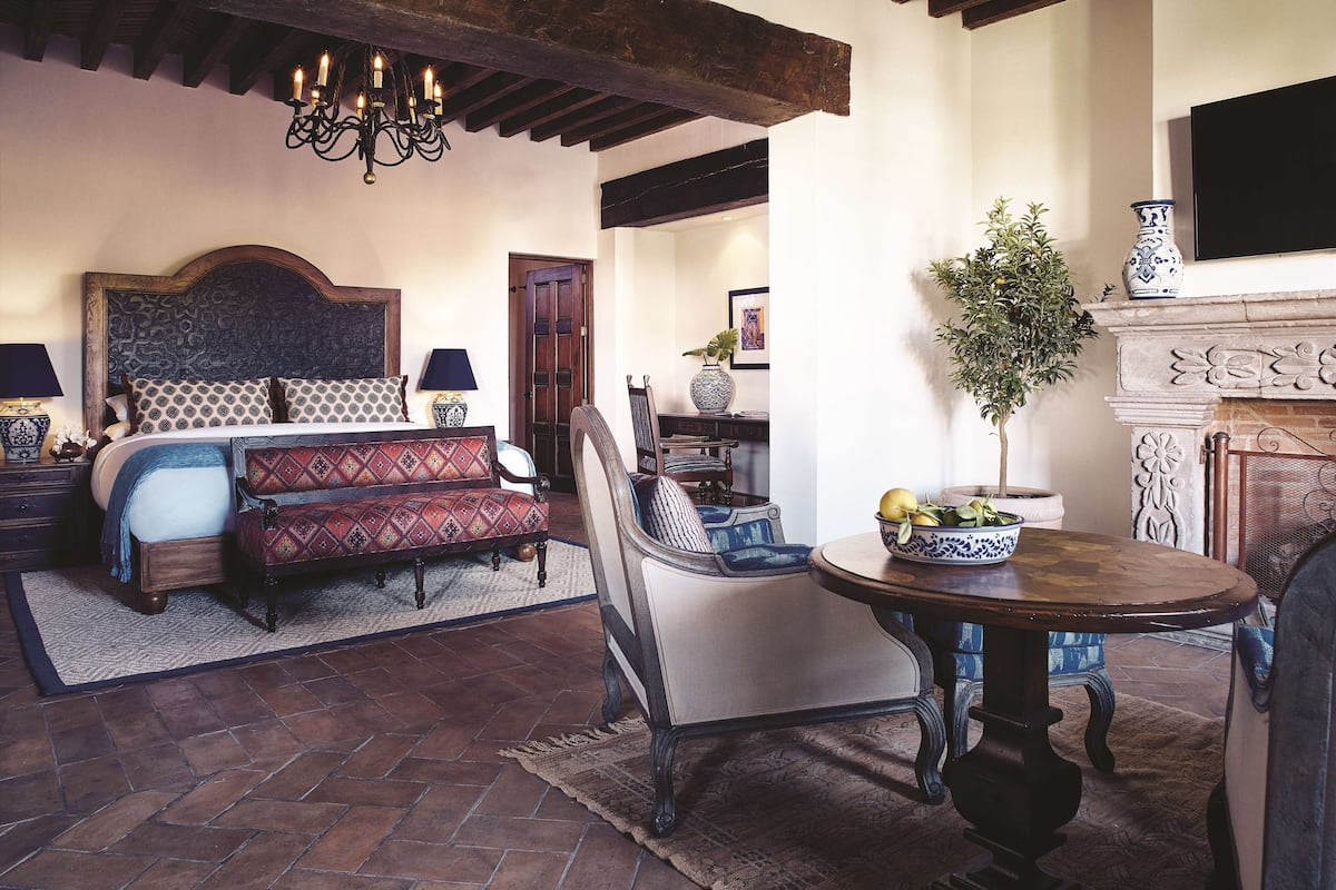 Un dormitorio con una cama grande, un sofá, una mesa de comedor y una chimenea.