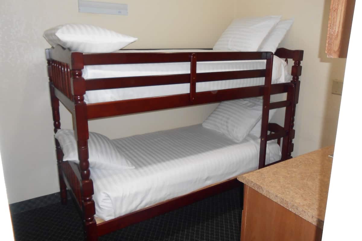 A bunk bed with white bedding and a wooden frame.