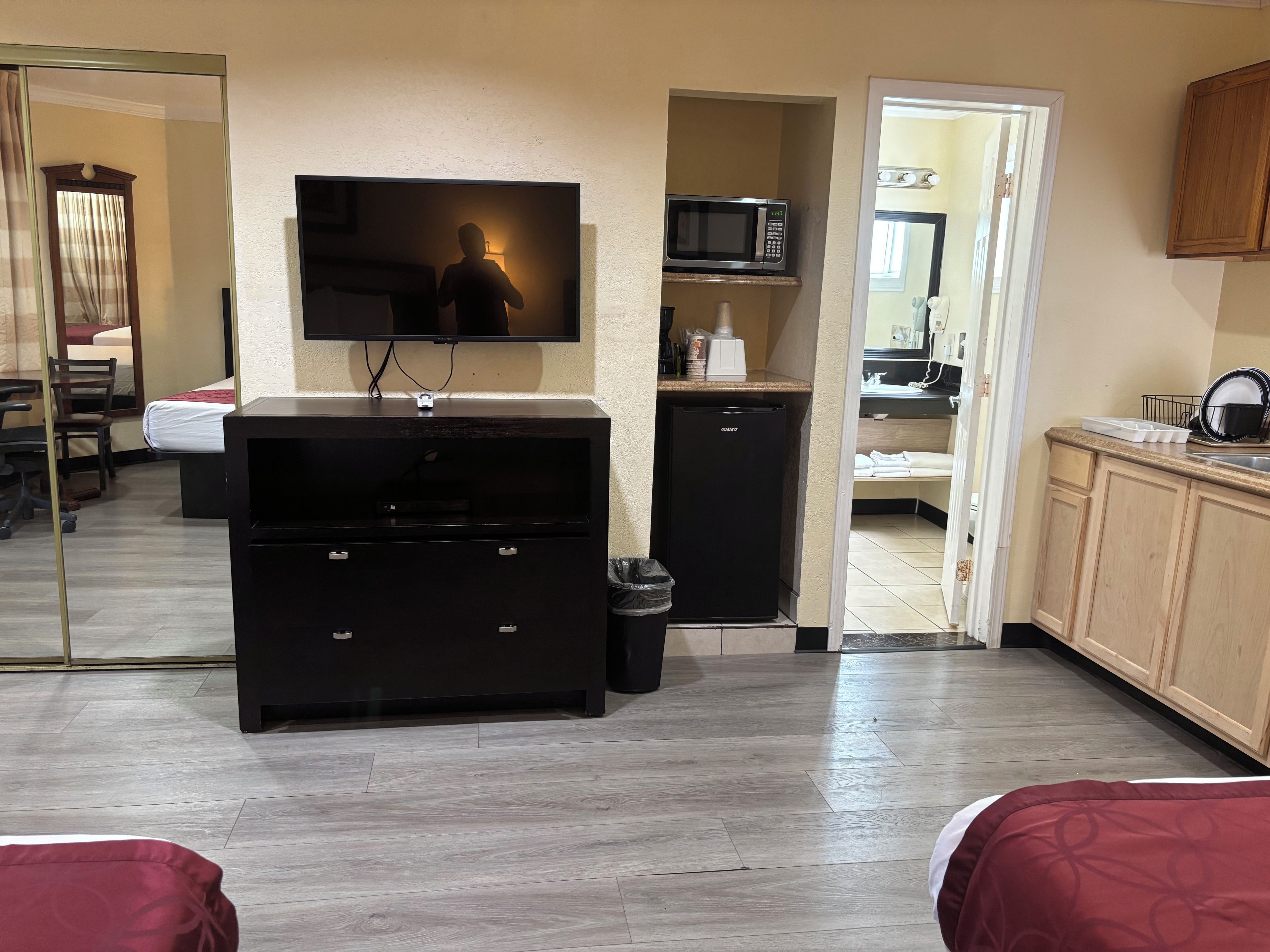 Una habitación de hotel con cama, televisión, minibar, microondas y kitchenette.