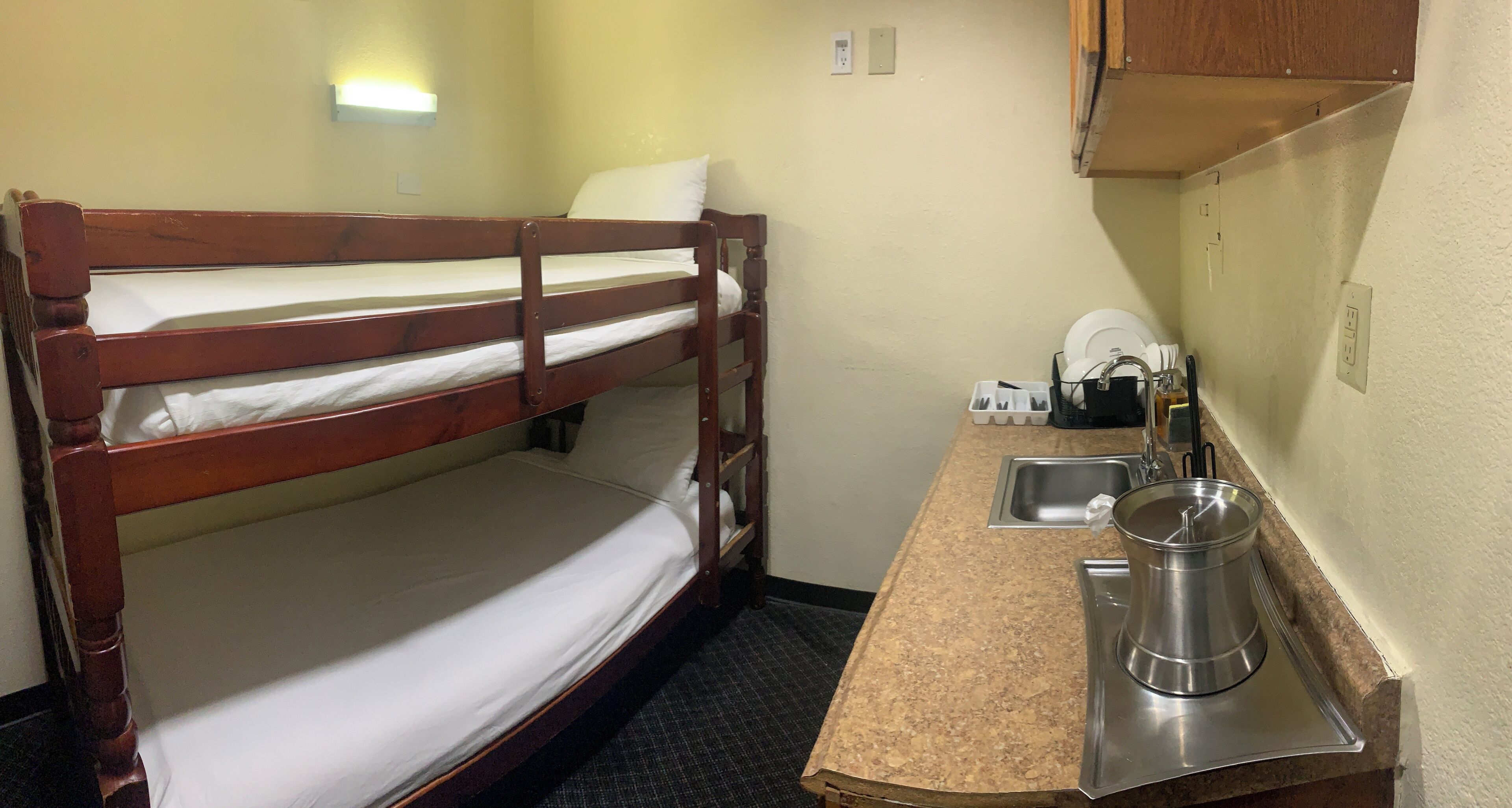 Ein Stockbett mit Spüle und Wasserkocher auf einer Arbeitsplatte.