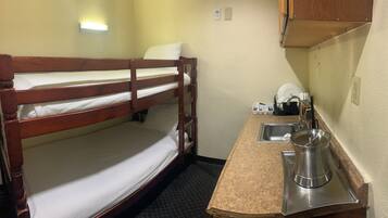A bunk bed with a sink and a kettle on a countertop.