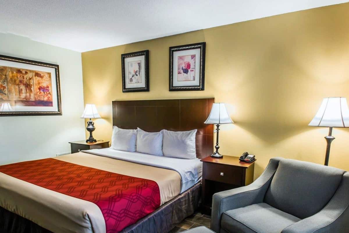 Une chambre d’hôtel avec un lit, deux tables de chevet avec des lampes, une chaise et une petite table.