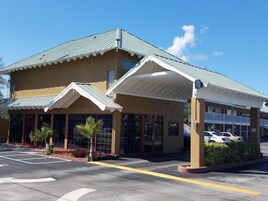 Un hotel de dos pisos con entrada cubierta y estacionamiento.