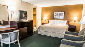 Een hotelkamer met een bed, een bureau met een televisie, een stoel en een lamp.