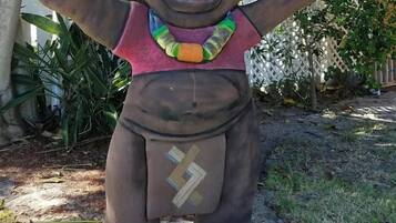 A statue of a figure with outstretched arms, wearing a necklace and a belt with lightning bolt symbols, standing on a base labeled "LOCO."