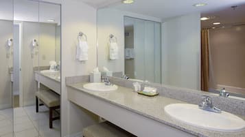 Un baño moderno con dos lavamanos, un espejo grande y un banco.