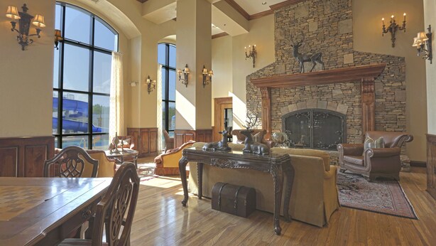 A spacious living room with a stone fireplace, large windows, and wooden furniture. - Music Road Resort Hotel and Inn (Pigeon Forge)