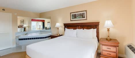 A hotel room with a large bed, a bathroom with a bathtub, and a mirror.