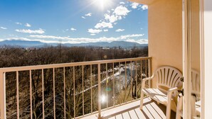 A balcony with a view of mountains and trees, a white chair, and a railing. - Music Road Resort Hotel and Inn (Pigeon Forge)