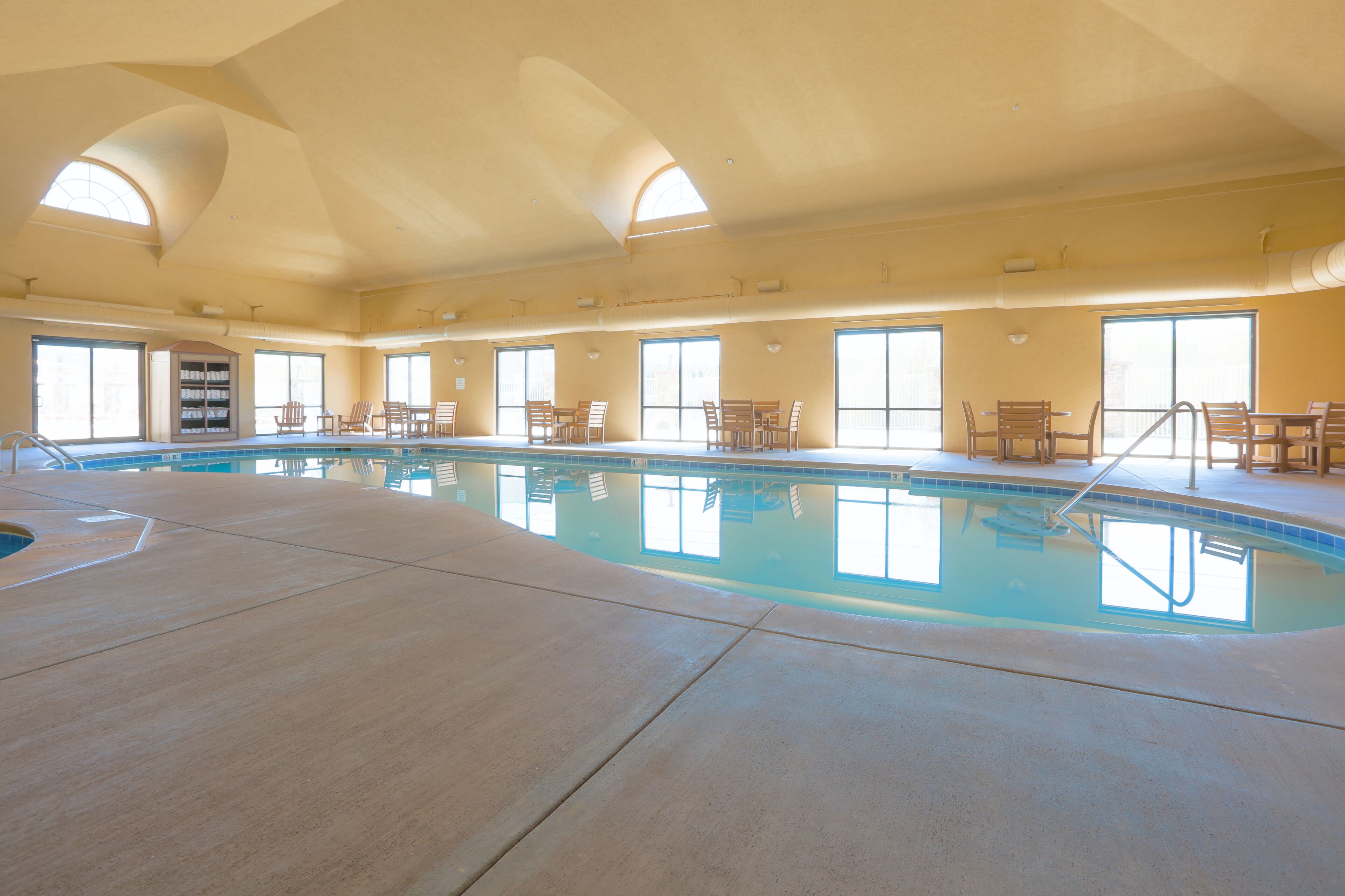 Ein Hallenbad mit hoher Decke, großen Fenstern und mehreren Sitzbereichen.