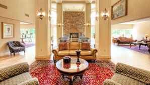 A spacious living room with a stone fireplace, leather sofas, and patterned rugs. - Music Road Resort Hotel and Inn (Pigeon Forge)