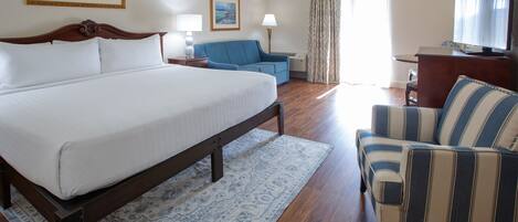 Una habitación de hotel con una cama grande, un sofá, un televisor y un escritorio.