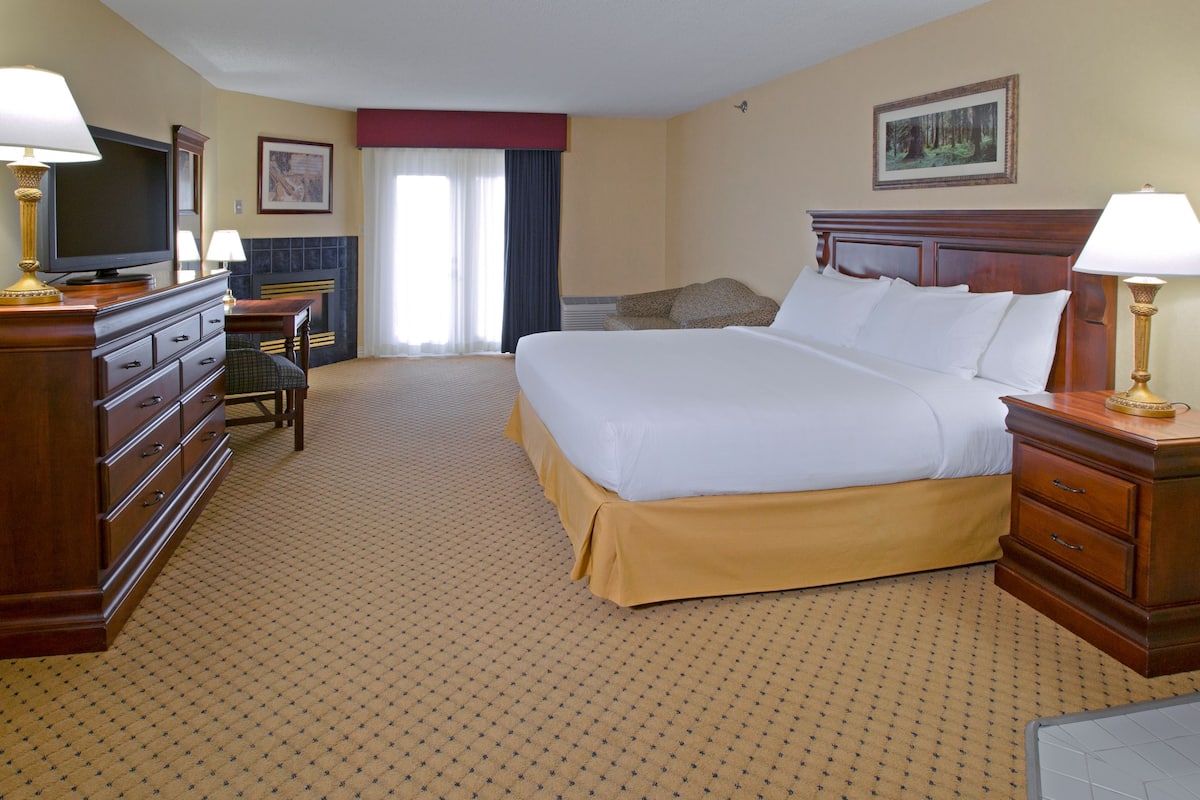 Quarto de hotel com uma cama grande, televisão, escrivaninha e cadeira.