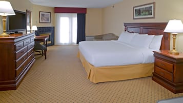 Una habitación de hotel con una cama grande, televisión, escritorio y una silla.